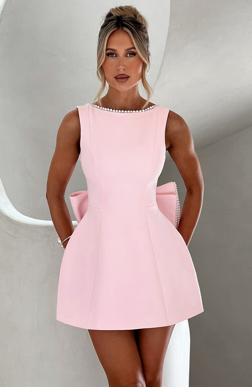 Woman wearing the pink pearl trim a-line mini dress with a statement bow