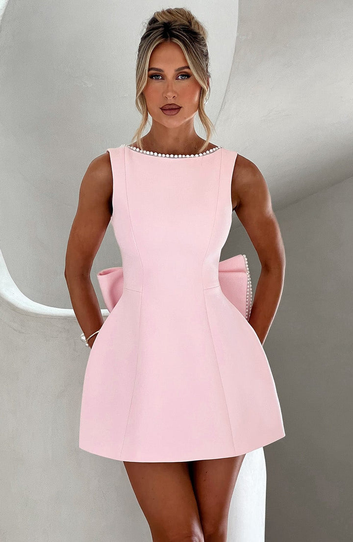Woman wearing the pink pearl trim a-line mini dress with a statement bow