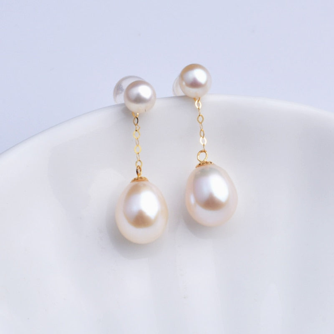 Close-up of elegant pearl drop earrings resting on a white dish
