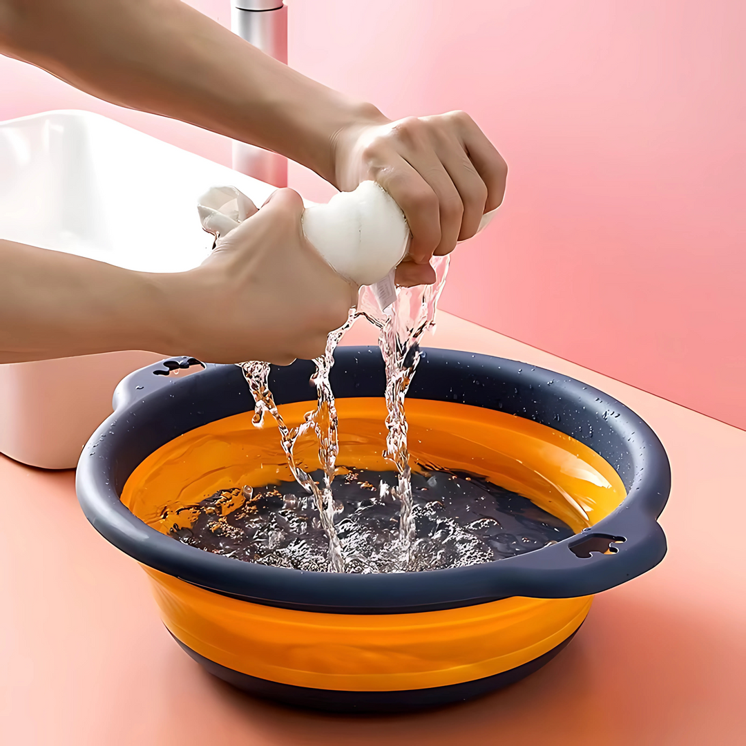 Hands washing fabric inside a dark blue foldable basin