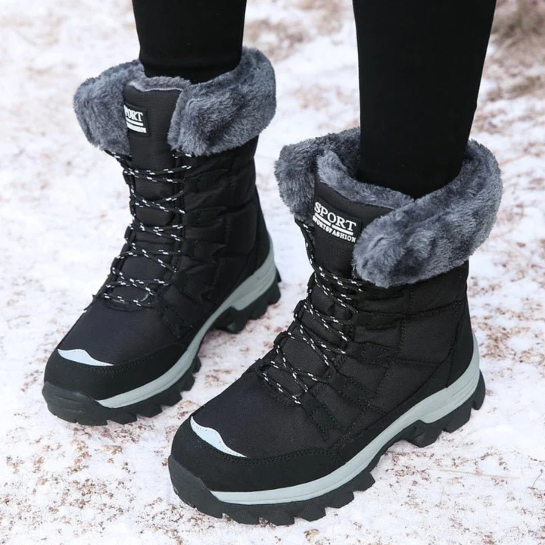 Black women's winter snow boots with grey faux fur trim and grip soles on snow
