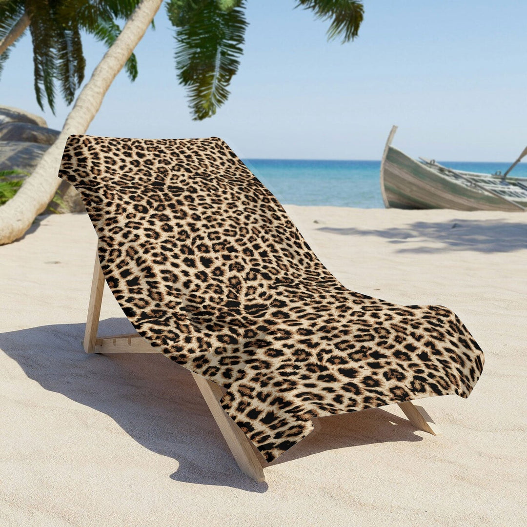 Leopard print beach towel spread across a lounge chair on the sand