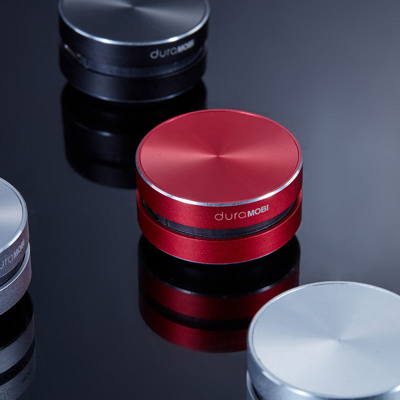 Red and silver portable surface audio speakers on a dark reflective surface