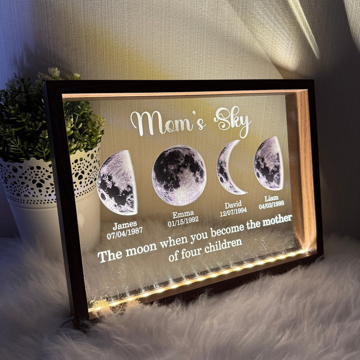 Illuminated custom family moon phase frame glowing on a soft surface