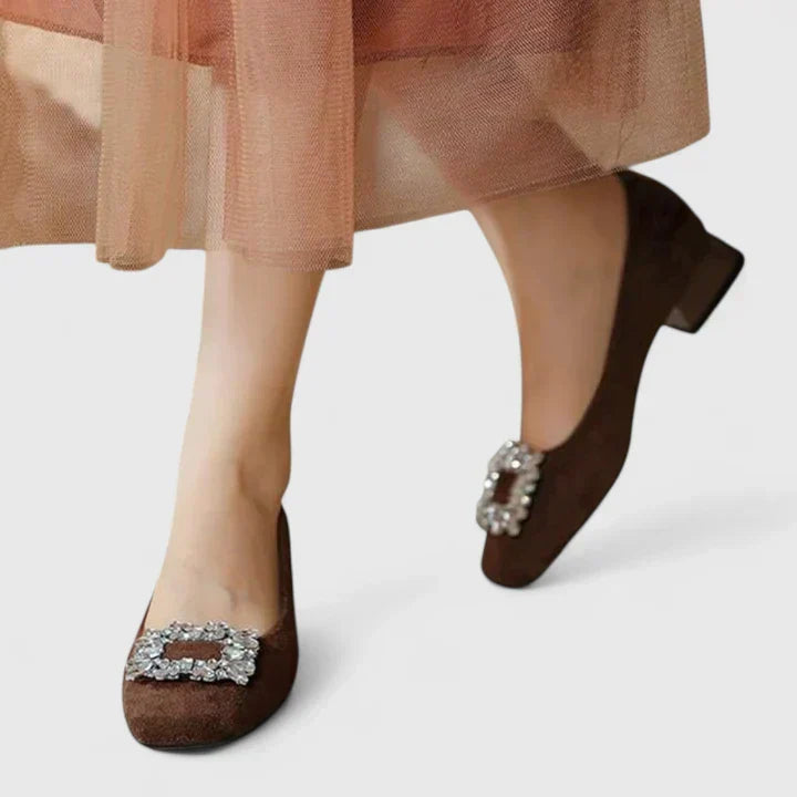 Side angle view of brown comfortable low block heels worn with a pleated skirt