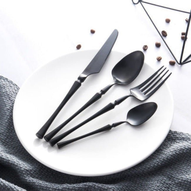 Matte black stainless steel cutlery set displayed on a white plate