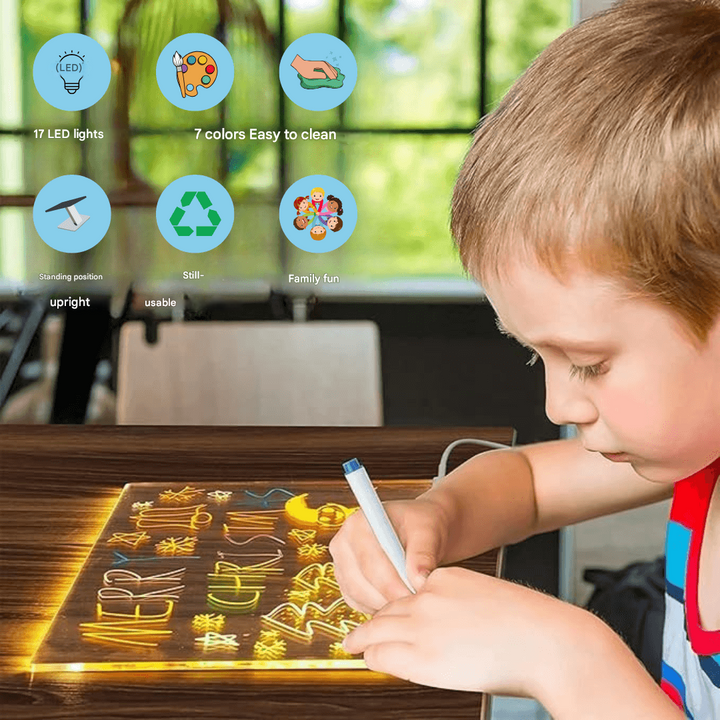 Young boy writing on a glowing LED drawing board at a desk