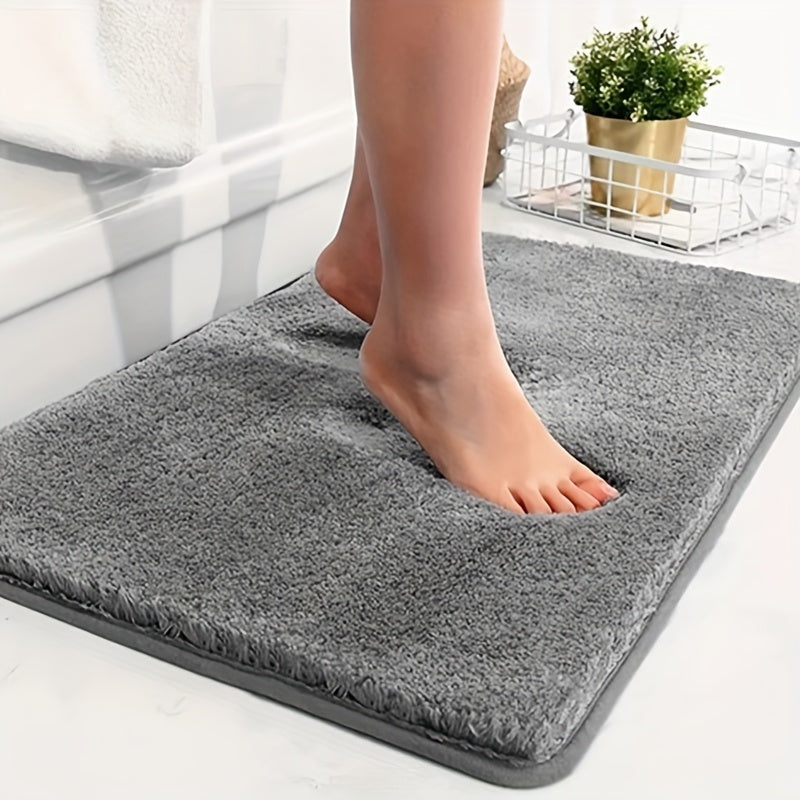 Grey absorbent bath mat on a white tiled floor with bare feet standing on it
