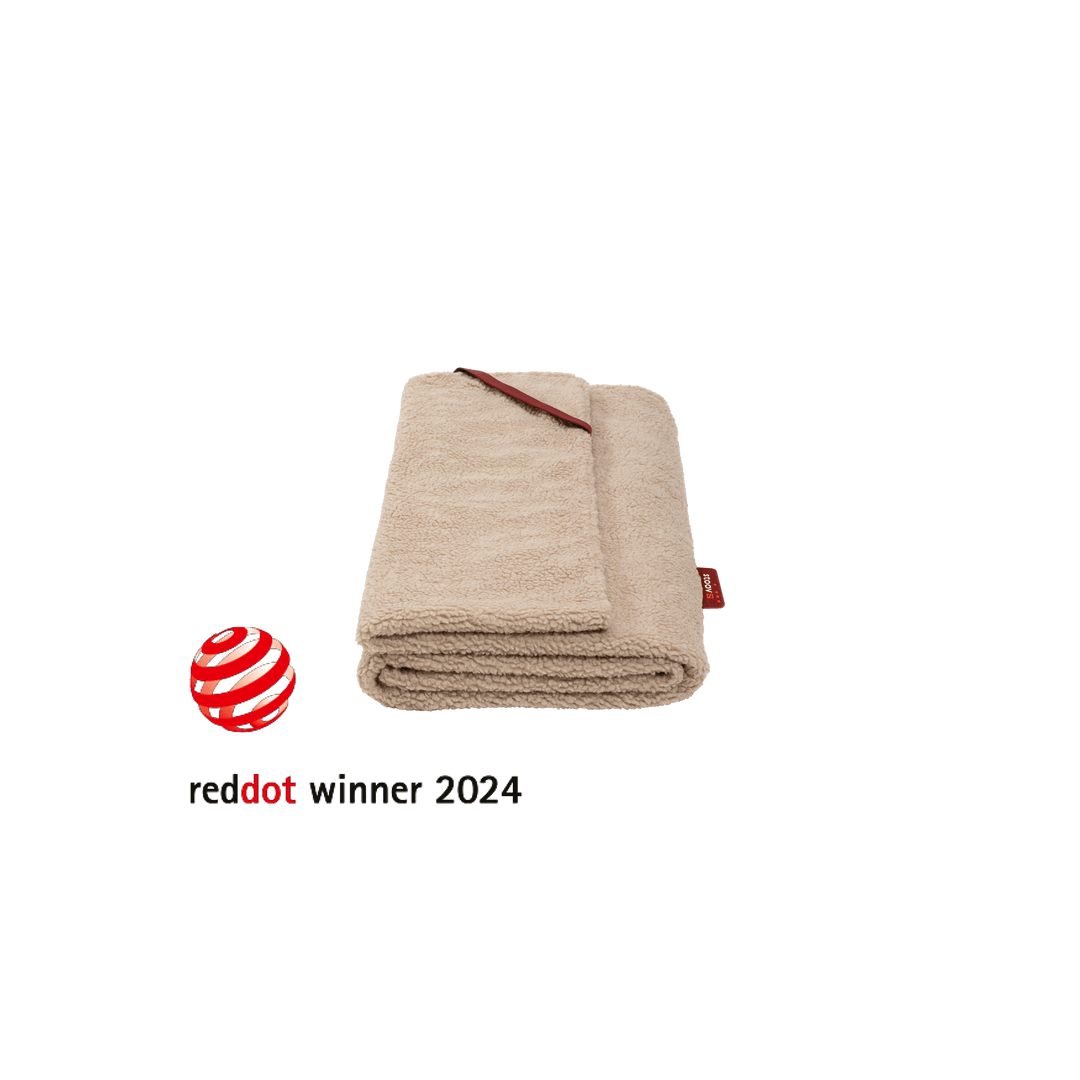 Folded beige plush blanket with red label and Red Dot winner 2024 logo