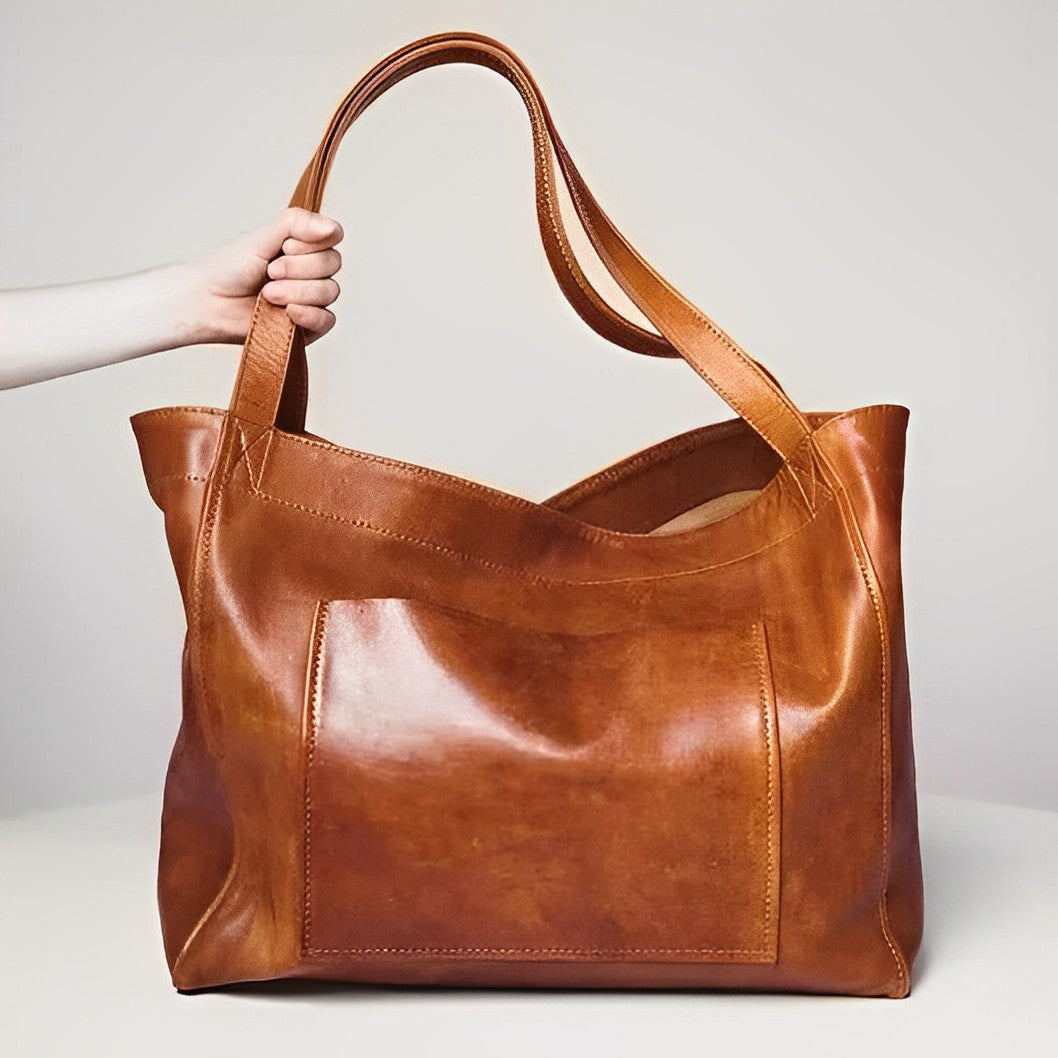 Brown vintage shoulder bag held by hand displaying main body and handles