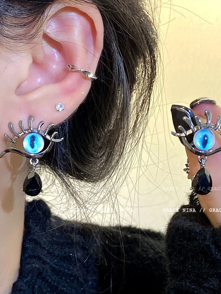 Close-up of woman wearing detailed evil eye drop earrings with blue stone