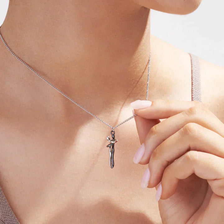 Close-up of a person wearing the couples hugging pendant necklace