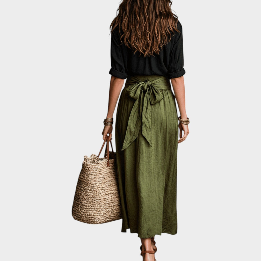 Back view of a woman wearing a black top and green maxi skirt set
