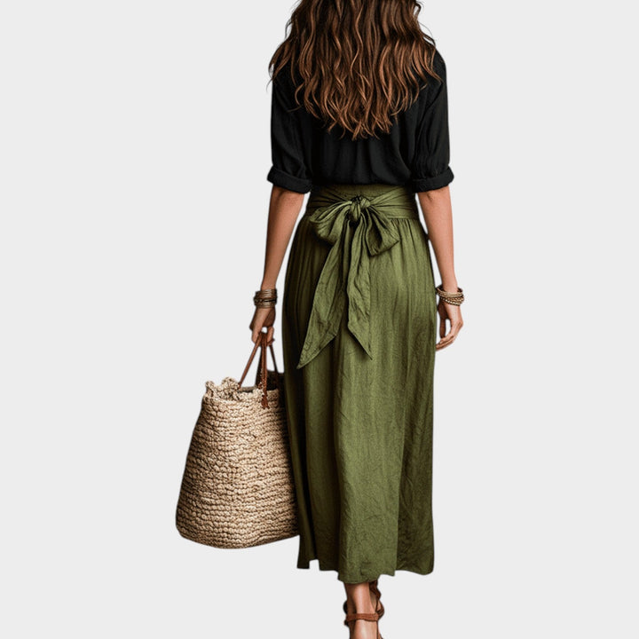 Back view of a woman wearing a black top and green maxi skirt set