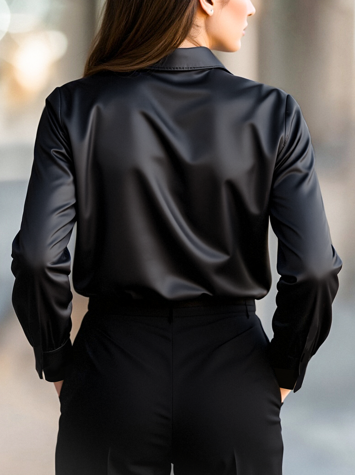 Back view of a woman wearing a black long sleeve blouse paired with tailored trousers