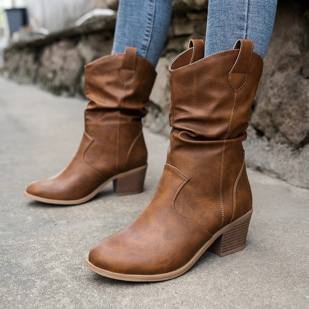 Close-up of brown mid-calf boots paired with blue jeans showing textured upper