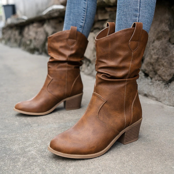 Close-up of brown mid-calf boots paired with blue jeans showing textured upper