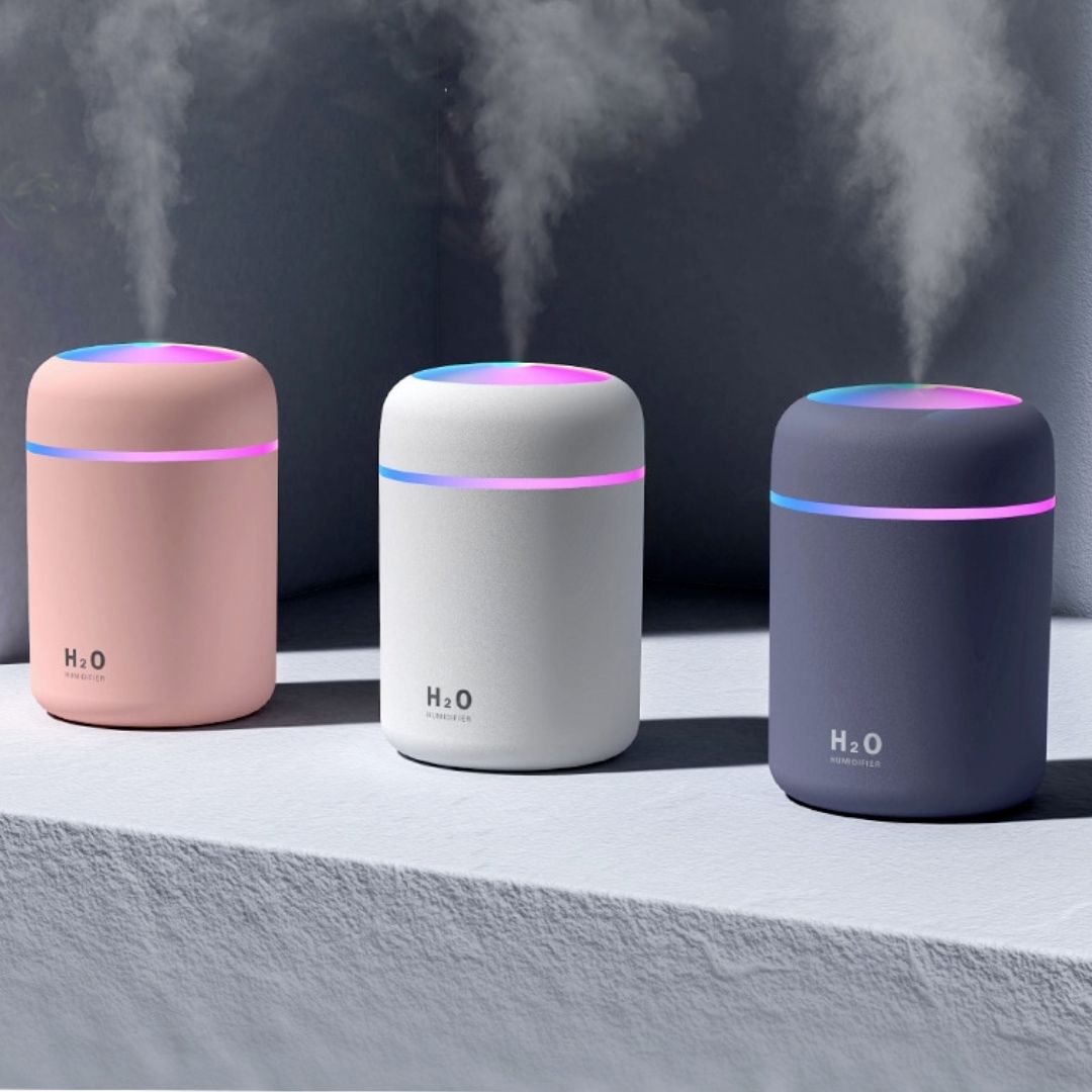 Three mini H2O humidifiers in pink, white, and grey emitting mist