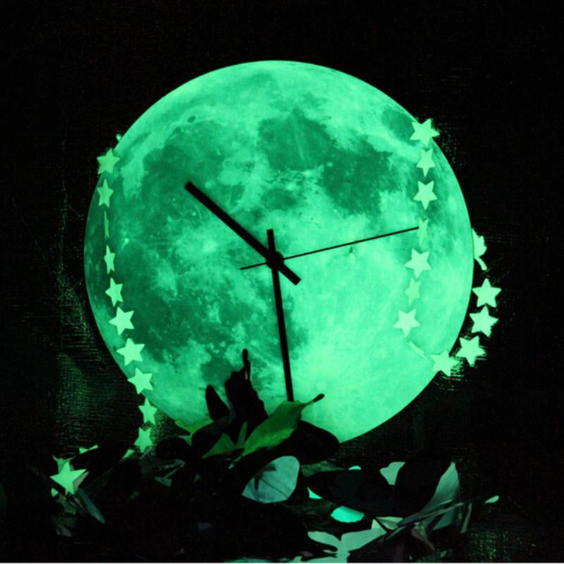 The moon wall clock glowing brightly in a dark room with decorative star accents.