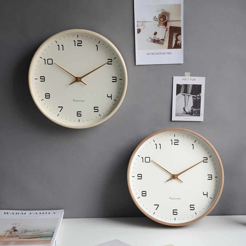Two Scandinavian wooden wall clocks in brown and cream mounted on a grey wall.