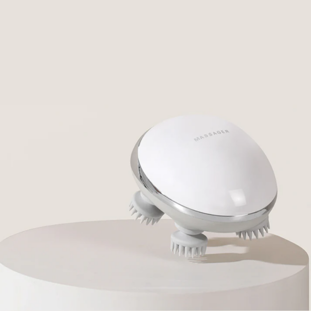 Cordless electric scalp massager showing flexible silicone massage nodes on a minimalist display