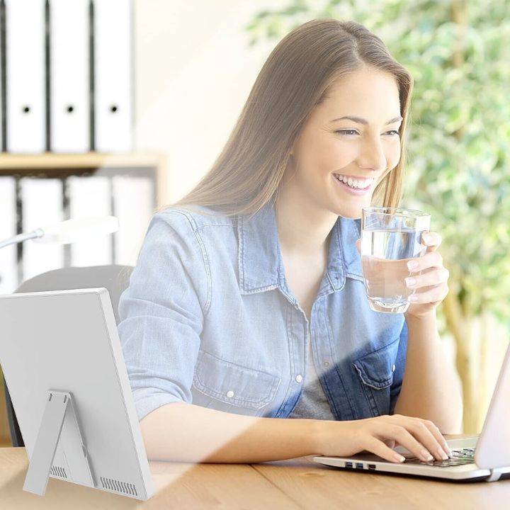 Woman working at a desk next to a portable light therapy lamp
