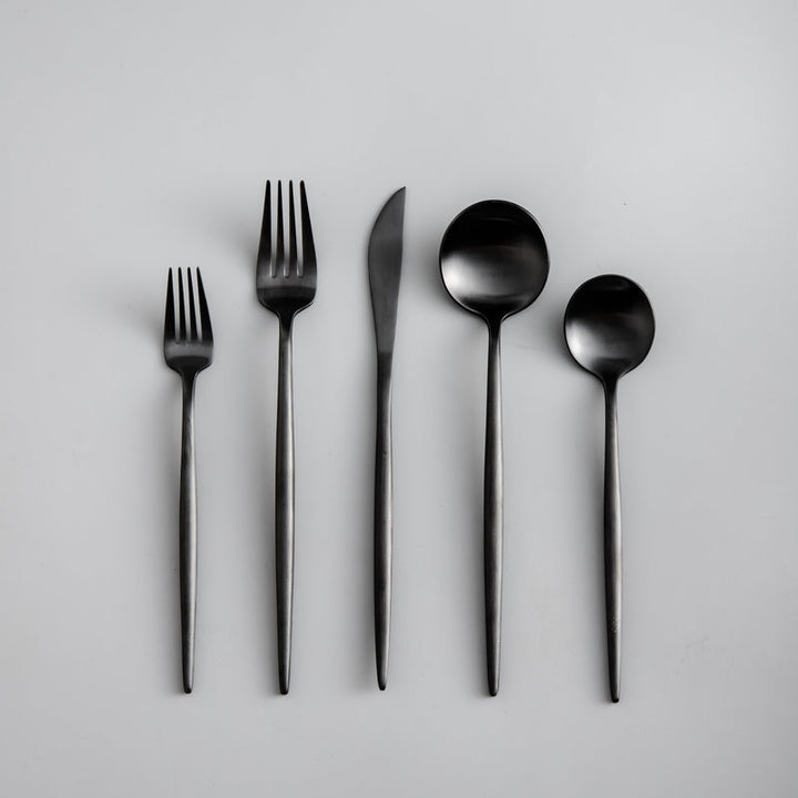 Full layout of a matte black cutlery set featuring minimalist modern design