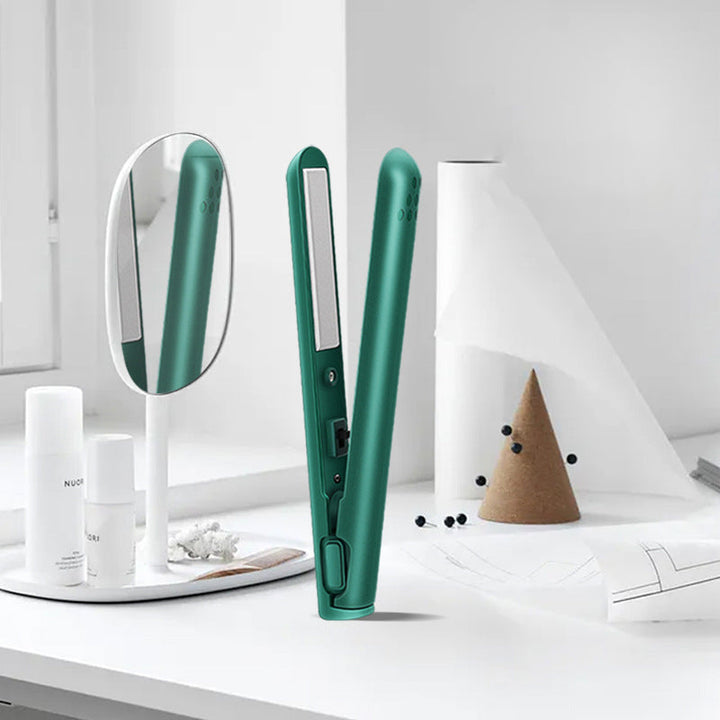 Open green mini hair straightener on a clean white vanity table next to cosmetic bottles