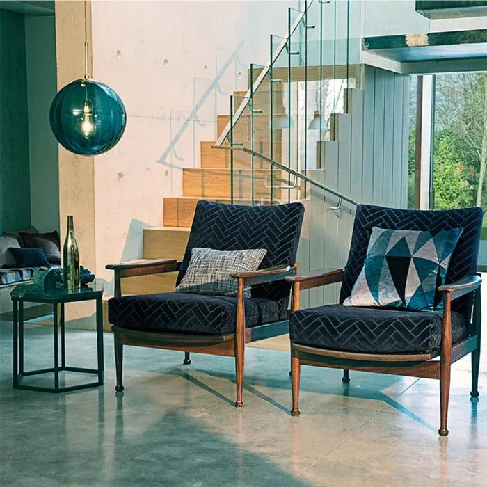 Single blue glass globe pendant light suspended near a staircase and armchairs