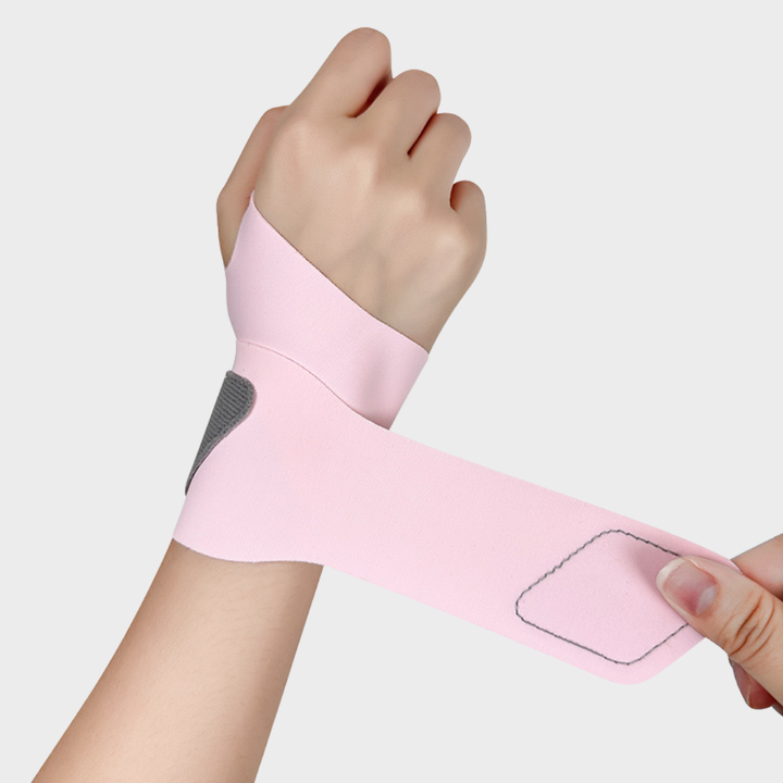 Close-up of a hand demonstrating the adjustable hook and loop closure on a pink wrist wrap