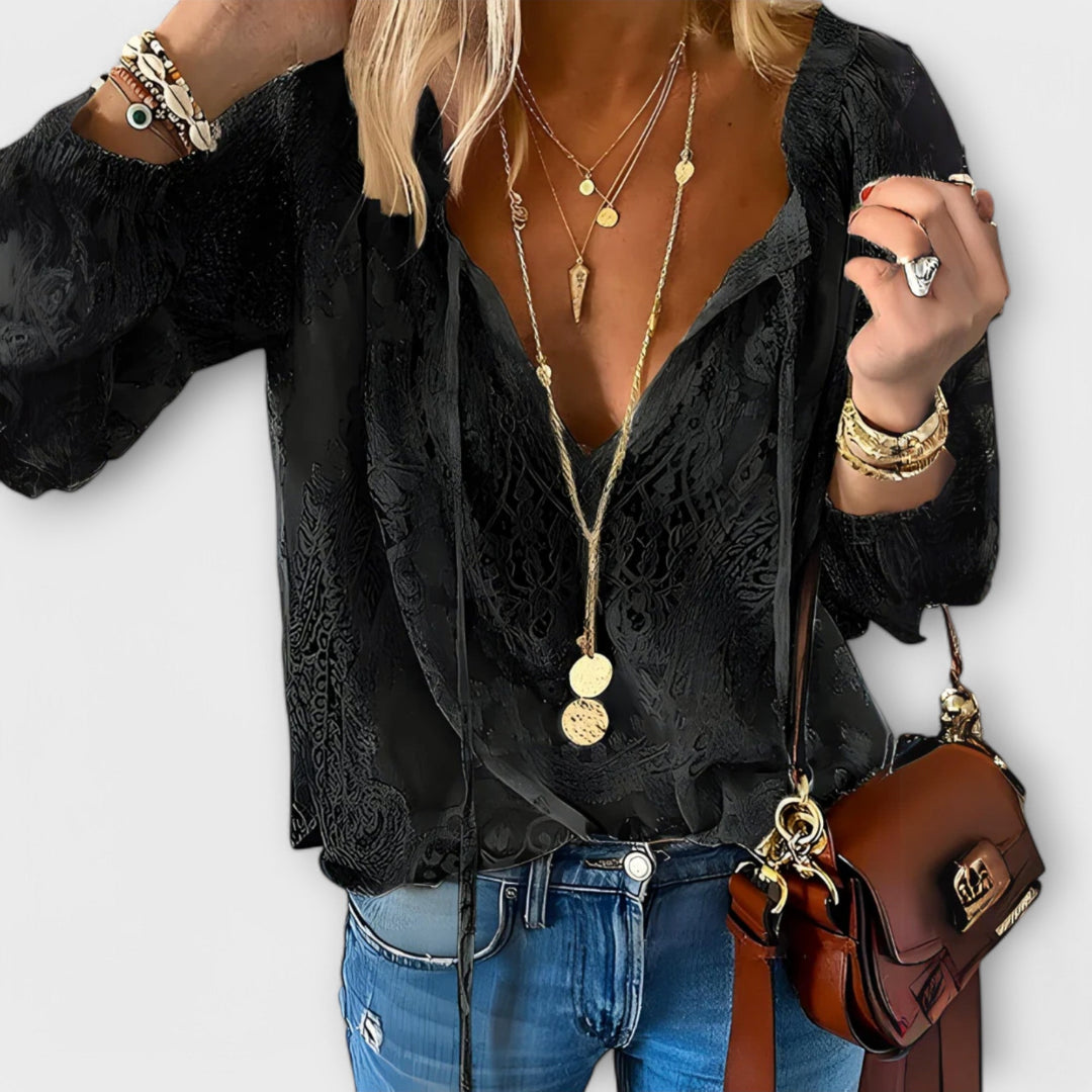 Model wearing black lace overlay V-neck blouse holding a brown handbag