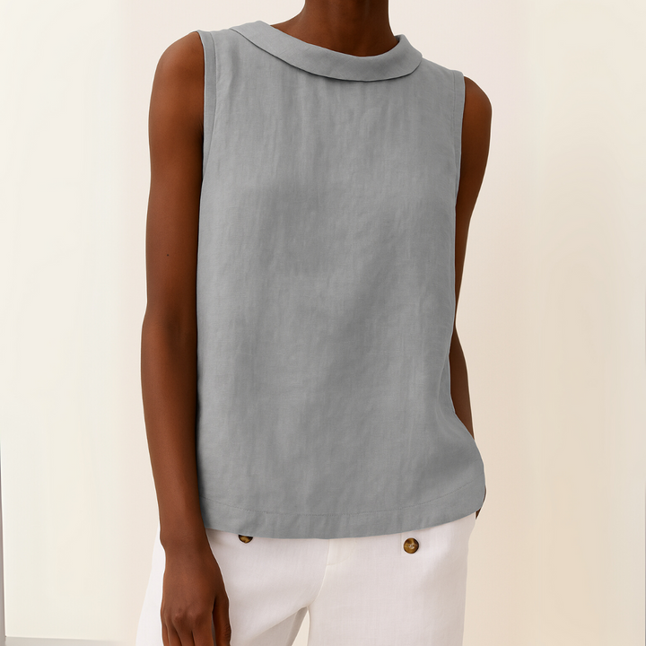Front view of a model wearing a grey sleeveless roll collar relaxed summer top with white trousers