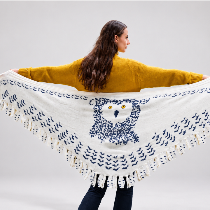 Studio shot of woman wearing the owl knitted shawl against a plain background