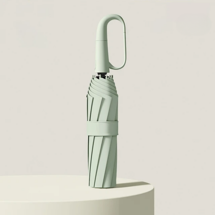 Compact green automatic windproof umbrella standing upright on a podium