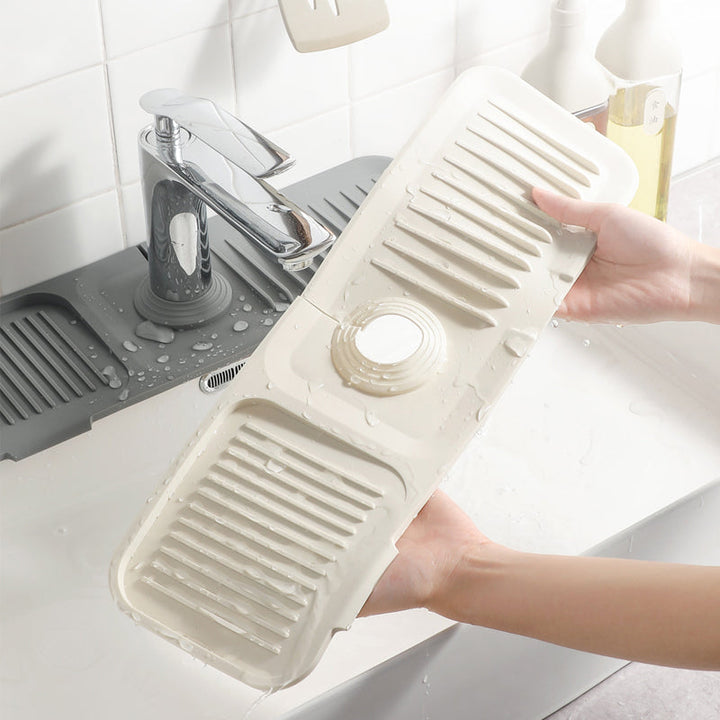 Close-up of a beige silicone dish drying mat near a modern kitchen faucet