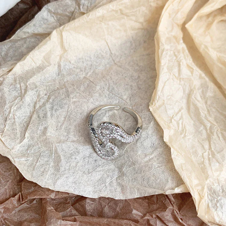 Close-up of the S-shaped statement ring resting on textured paper