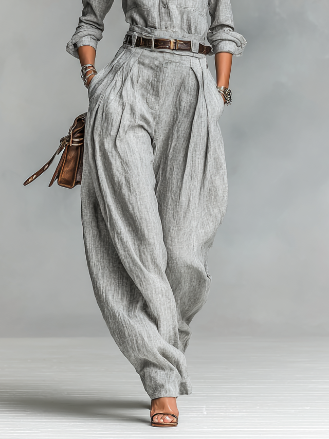 Detailed view of the high-waisted gray wide-leg trousers with a stylish belt and deep pockets.