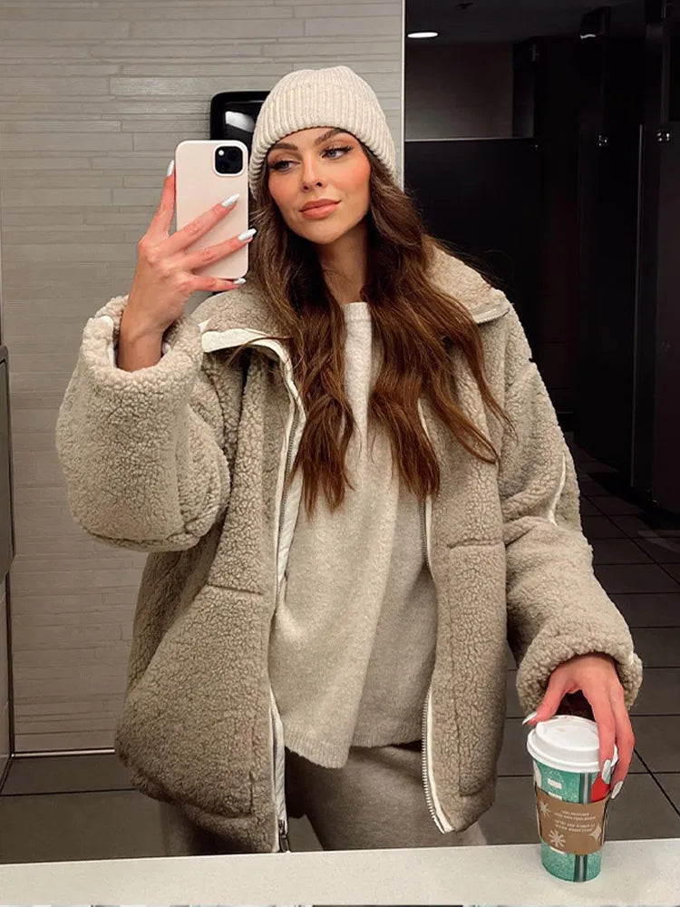 Woman wearing a teddy fleece jacket and beanie holding a cup of coffee