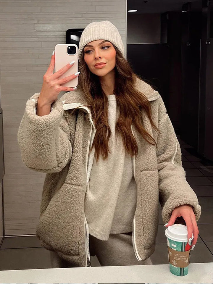 Woman wearing a teddy fleece jacket and beanie holding a cup of coffee