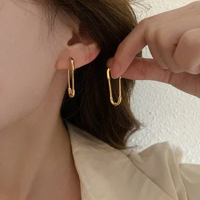 Woman wearing stylish gold paperclip drop earrings