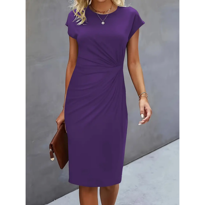 Woman wearing a violet blue short sleeve midi dress posing against a grey wall