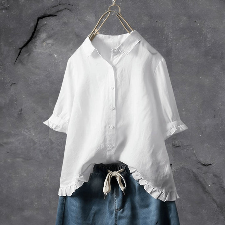 White women's button-front blouse featuring a decorative ruffle hem