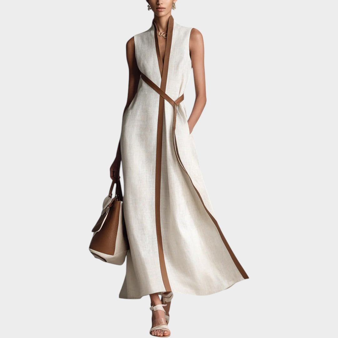 Woman wearing a white sleeveless maxi dress with brown contrast trim and matching handbag