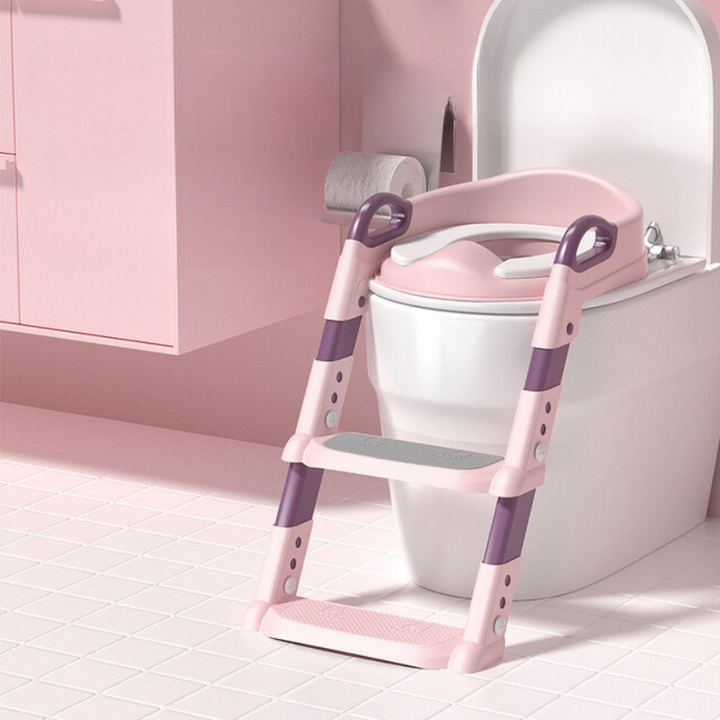 Pink toddler climbing potty training seat placed on a white toilet in a pink-themed bathroom