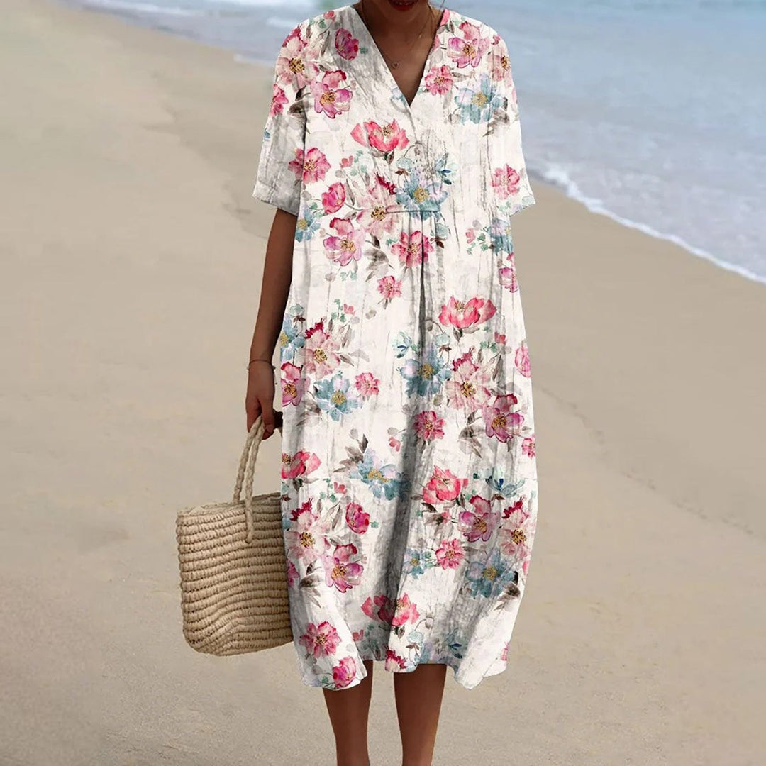 Woman wearing a vintage-inspired floral dress and holding a straw bag on the beach