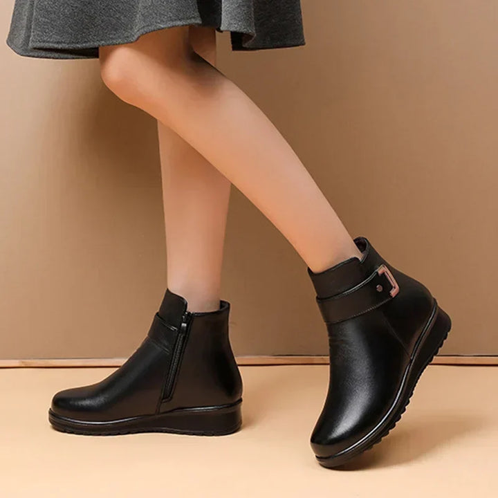 Side profile of women's black winter boots worn with a grey skirt