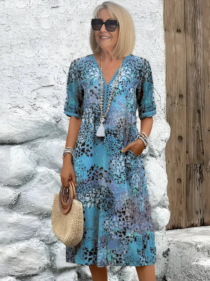 Mature woman wearing an ocean blue patterned mid-length dress with matching accessories