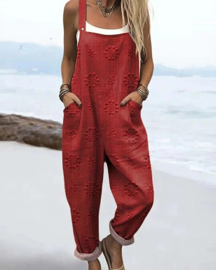 Model wearing red meadow glow floral jumpsuit by the water