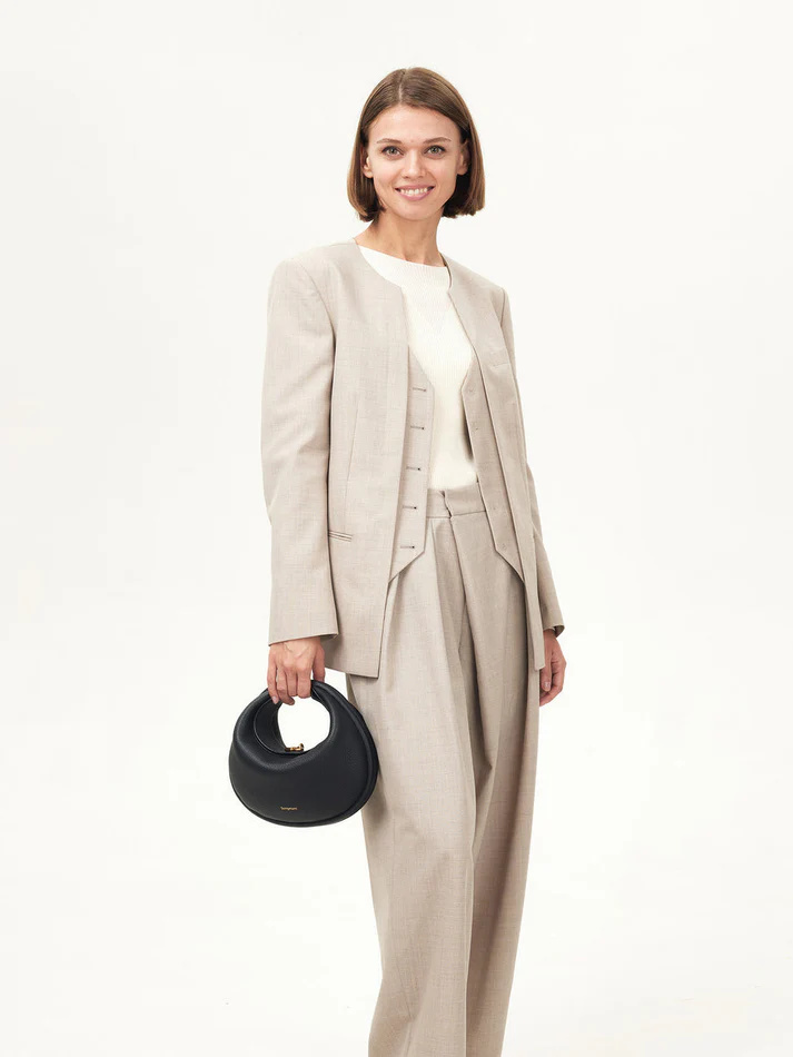 Model wearing neutral suit holding a black convertible handbag