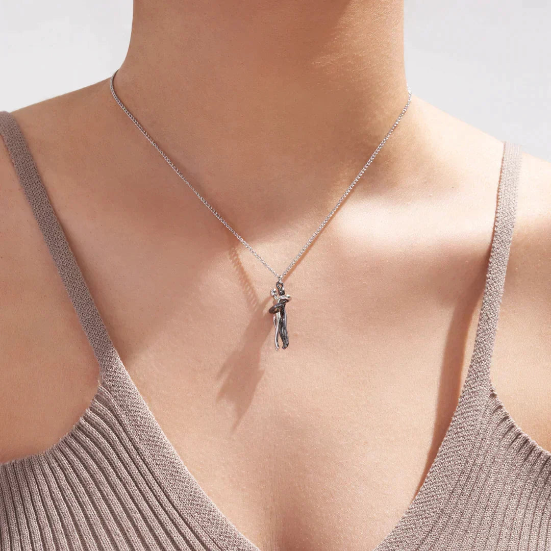 Unisex silver couples hugging pendant necklace on a clean white background